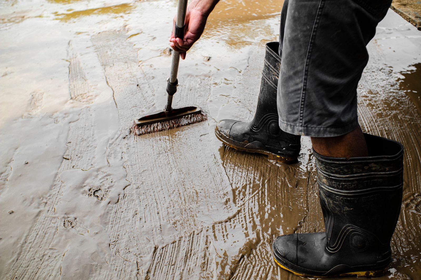 Pekerja mengaplikasikan lapisan pelindung pada lantai beton, ilustrasi waterproofing lantai dan dak